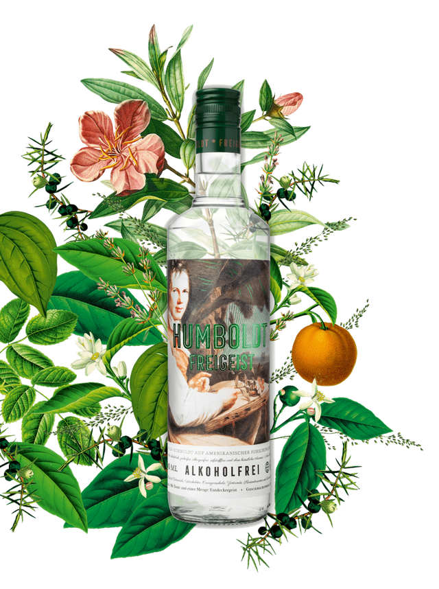 Eine Flasche Humboldt Freigeist steht im Mittelpunkt, umgeben von üppigen grünen Blättern und bunten Blumen.
